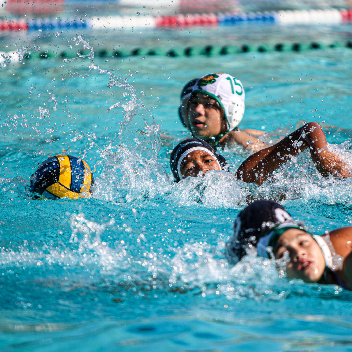 Competitive water polo play with players battling for the ball.