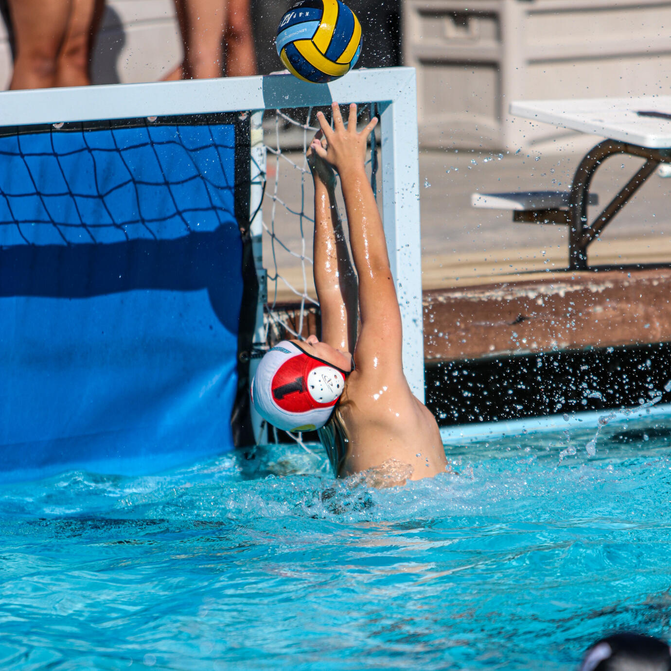 Water polo goalie blocking an intense shot on goal.
